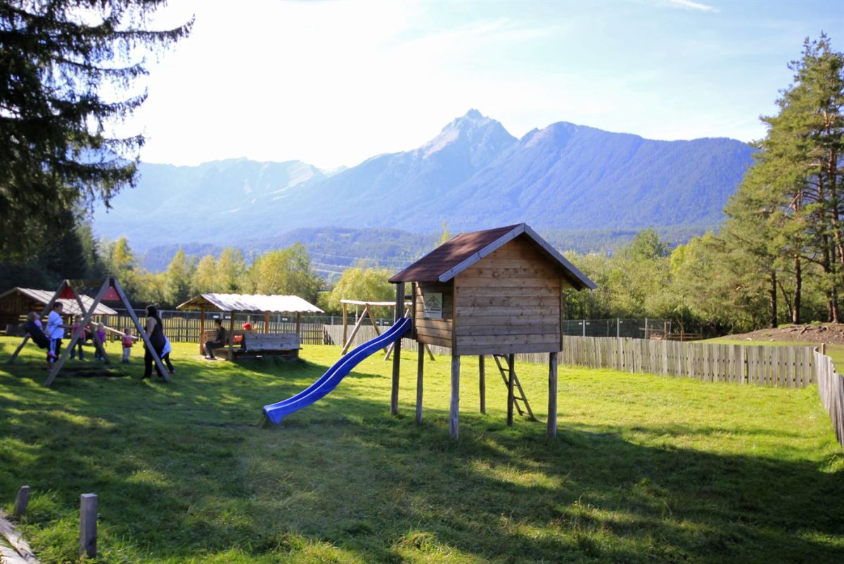Spielplatz der Happi's Hütte mit Holzhaus, Rutsche und Bergpanorama Tschirgant