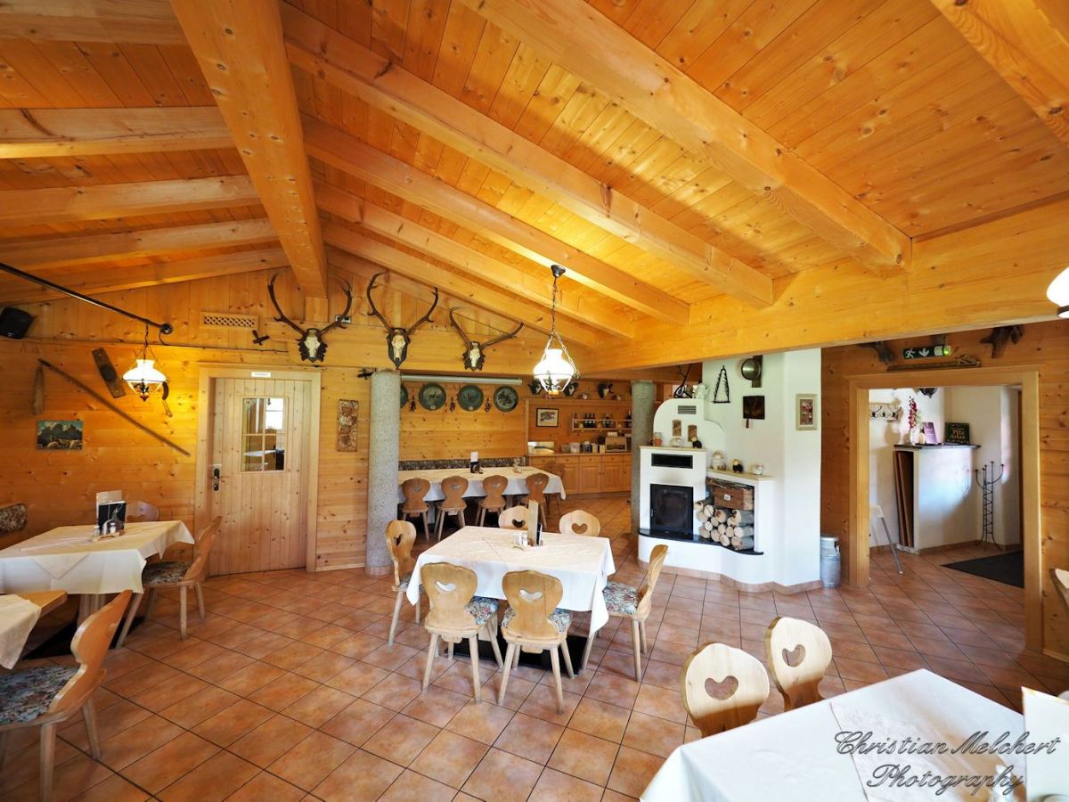 Stube der Happi's Hütte mit Kachelofen, Holzbalkendecke und herzförmigen Stuhllehnen