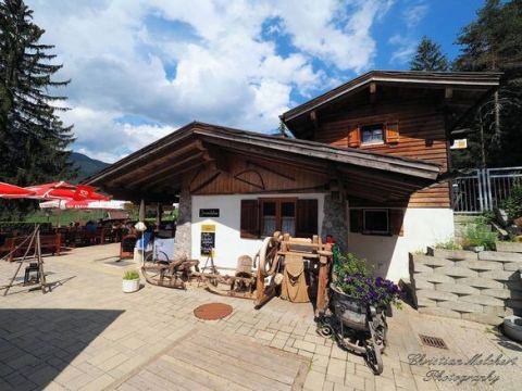 Außenansicht der Happi's Hütte im Sommer mit Sonnenschirmen und Tiroler Holzdekoration
