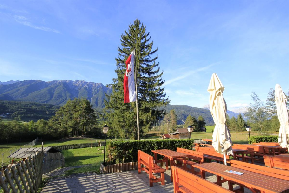 Terrasse der Happi's Hütte mit Tirol-Fahne und Panorama der Mieminger Berge im Gurgltal